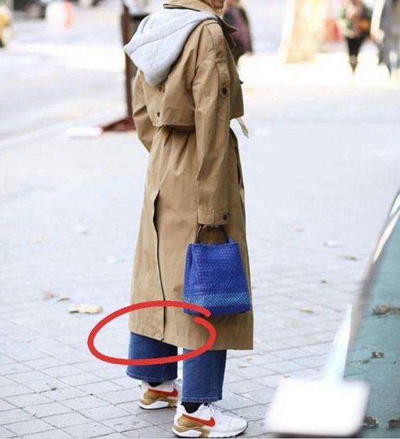 The woman is wearing  a beige trench coat. The vent stitch has not be opened.  I have circled it to indicate this.